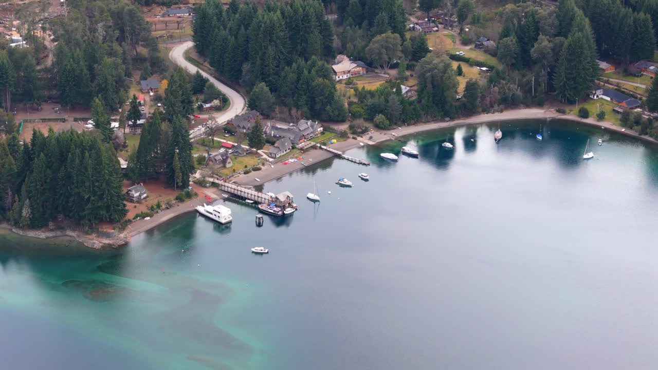Una pittoresca ripresa aerea con drone di imbarcazioni da diporto ormeggiate a Bahía Mansa a Villa La Angostura, Argentina, circondate da acque turchesi serene e una lussureggiante vegetazione naturale