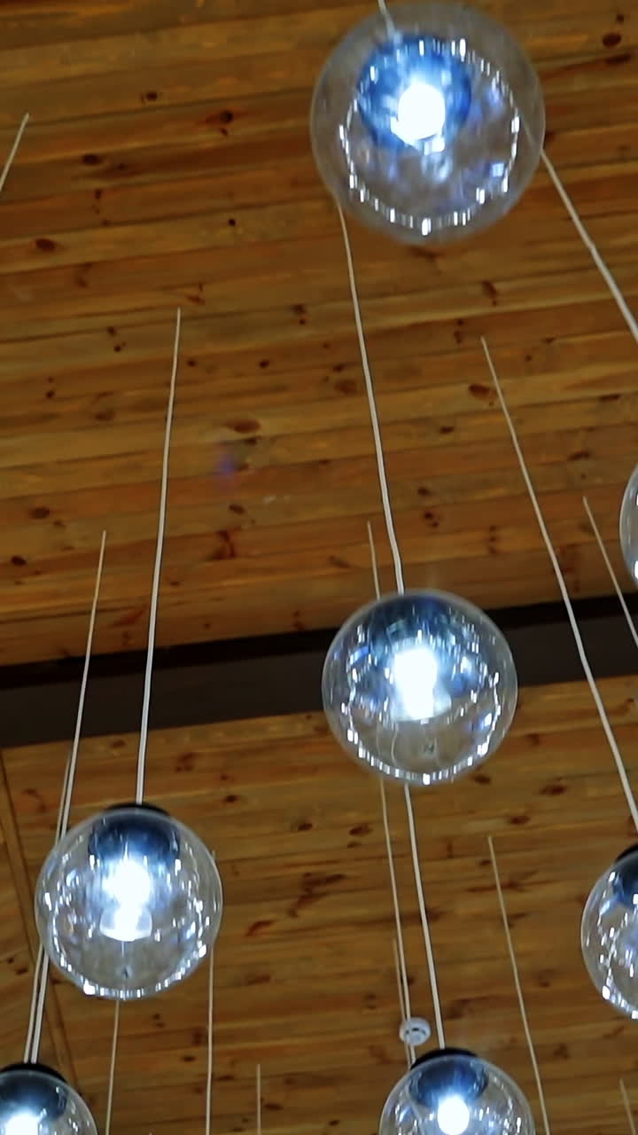 Cozy ceiling with many crystal small balls. Round light bulbs hanging on white wires. Modern design of shiny light lamps. Vertical video