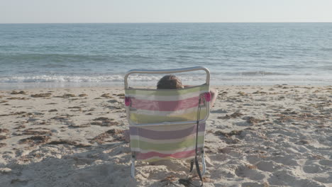 person relaxing on beach chair by the ocean