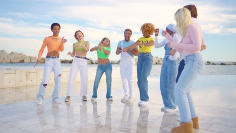multiracial friends dancing happily together next tot he sea