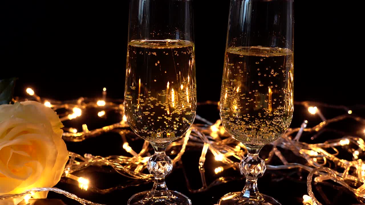Calici da champagne e una rosa sullo sfondo di ghirlande luminose