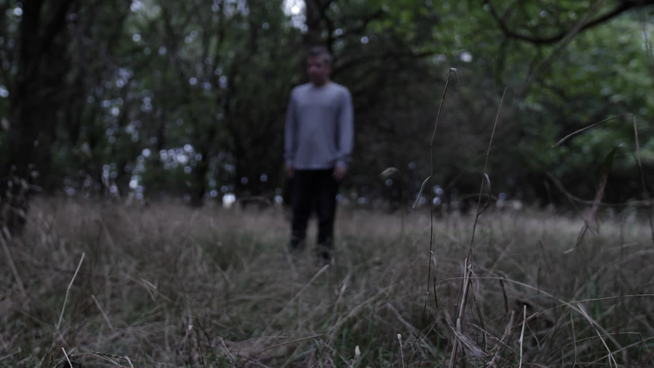 Depressed angry teen boy falls to his knees crying in the middle of a forest surrounded by trees