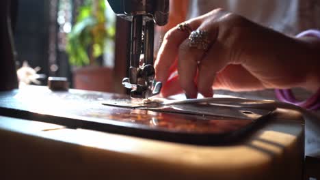 lady sewer on a manual sewing machine put a hem on the edge of a fabric in india. - close up shot