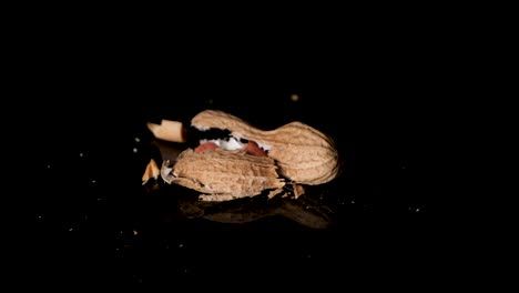 Peanut-is-cracked-with-fist-on-a-reflective-black-surface---Slow-Motion