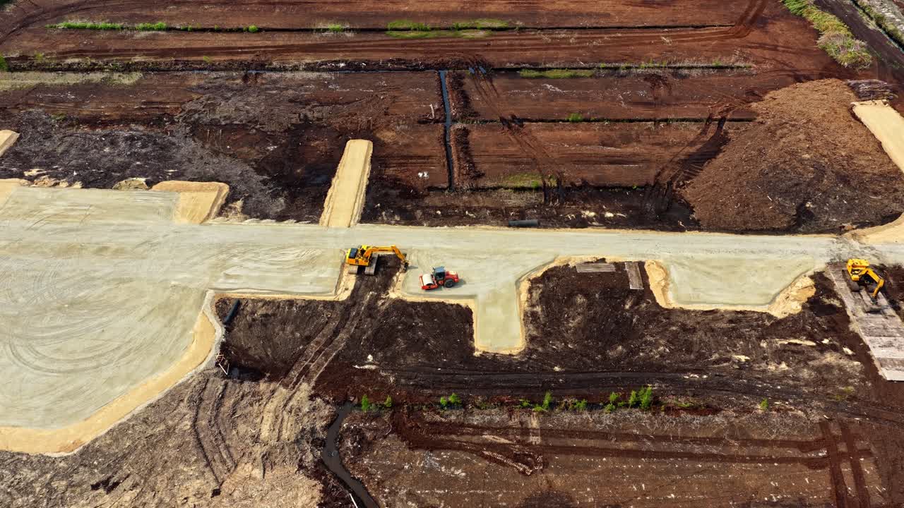 A drone glides past heavy machinery and excavators preparing land for new roads