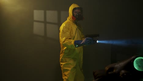 hombre vestido con traje de materiales peligrosos explora una habitación llena de humo