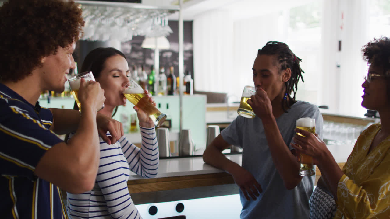 un grupo diverso de amigos felices bebiendo cervezas y hablando en un bar