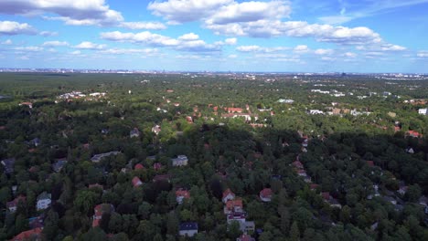 nikolassee, a residential district in berlin, featuring houses nestled within a dense forest, with the city skyline visible on the horizon. spectacular aerial view flight overflight flyover drone