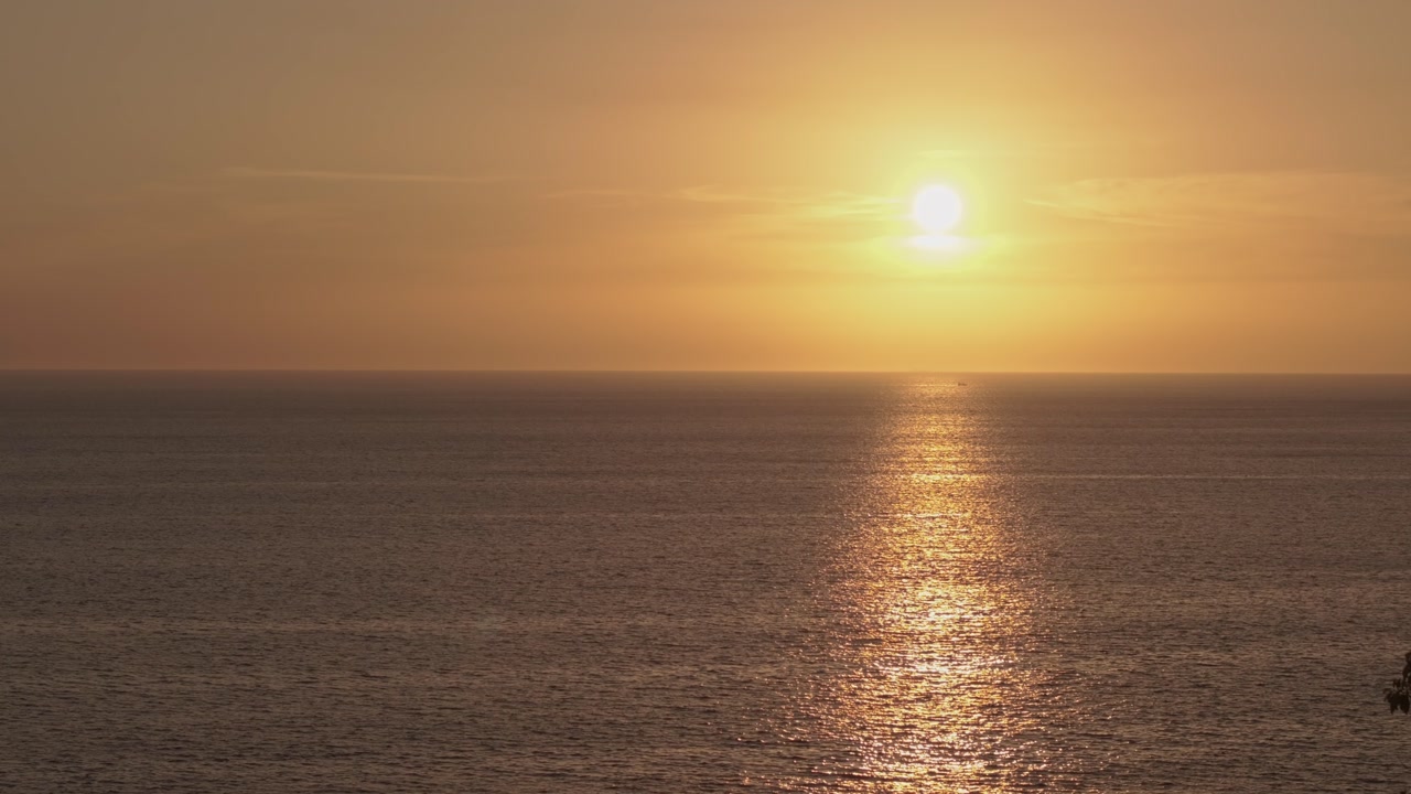 Aerial shot with a drone pointing towards the sun and passing over trees to then reveal the sea