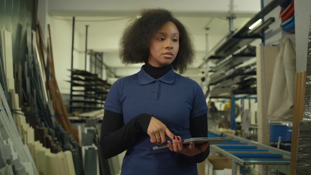 Ritratto di donna afroamericana che fa l'inventario in una fabbrica con un tablet per la gestione digitale moderna