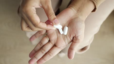 woman holding two white pills in her hand