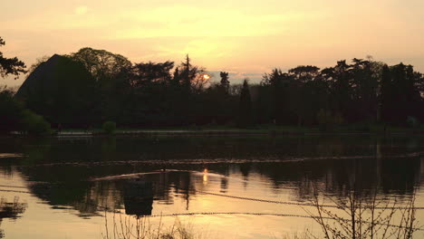 a static shot of the sunset over the lake in the vincennes woods in paris