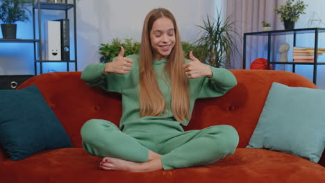 happy young teen girl looking approvingly at camera showing thumbs up, like positive sign, good news