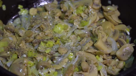 seasoning vegetable in frying pan on stove with mixed herbs and pepper, close up