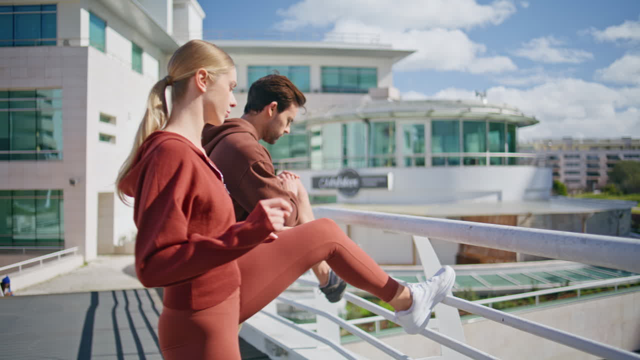 Active friends training together in sunny morning. Fit couple stretching legs
