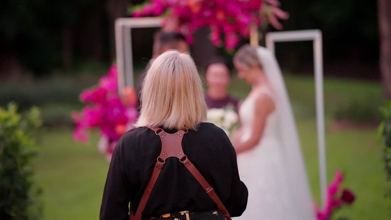 Focus Behind Blonde Wedding Photographer At Bright Outdoor Wedding Ceremony, 4K Slow Motion