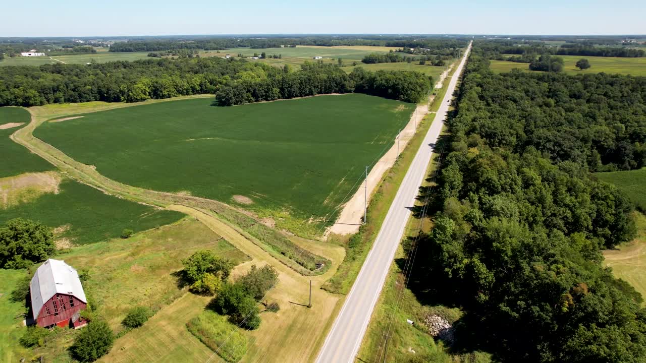 volando sobre el medio oeste país de la granja con granero rojo, campos y larga carretera recta