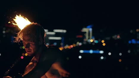 young blond male spins two burning pois slow motion close-up