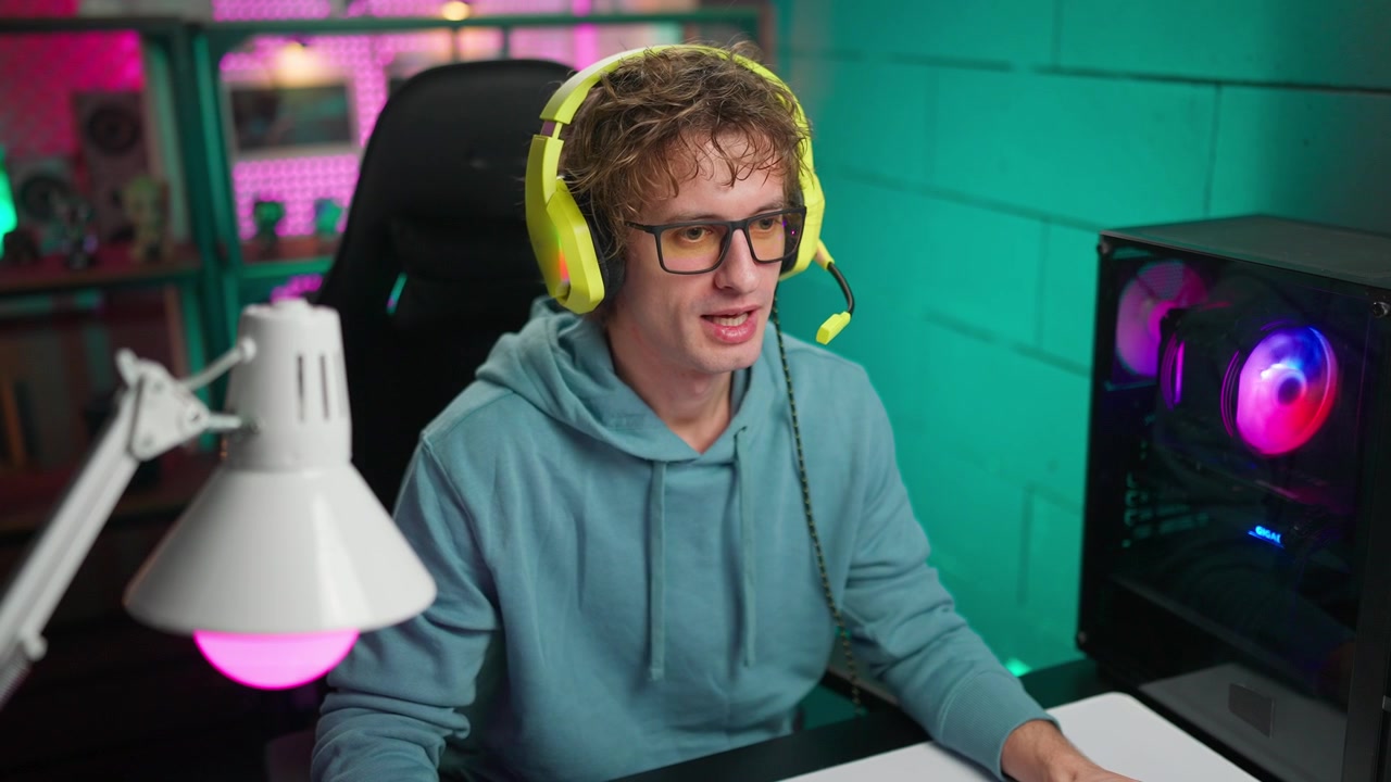 Young Man in Gaming Headset Talking at Computer Desk