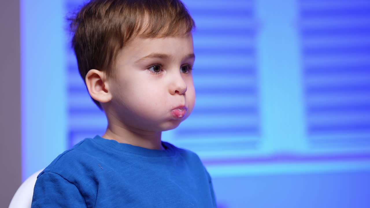 Toddler boy is holding dairy in his mouth. Baby boy points at something aside. Little kid drinks dairy from the bottle. Close up portrait.