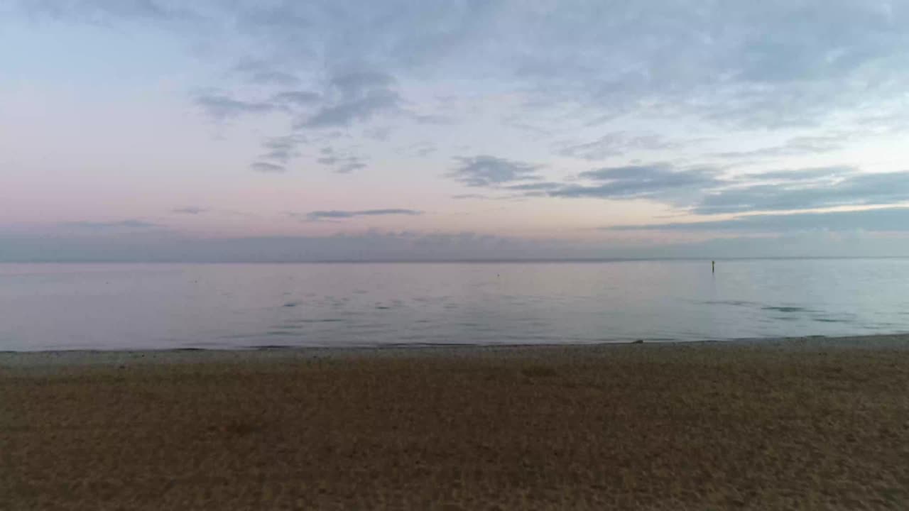 Drone flying over Beach shore and Calm blue tranquil bay with Soft clouds in horizon
