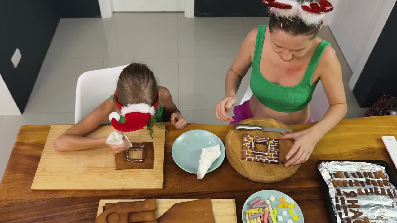 madre e hija decorando una casa de pan de jengibre
