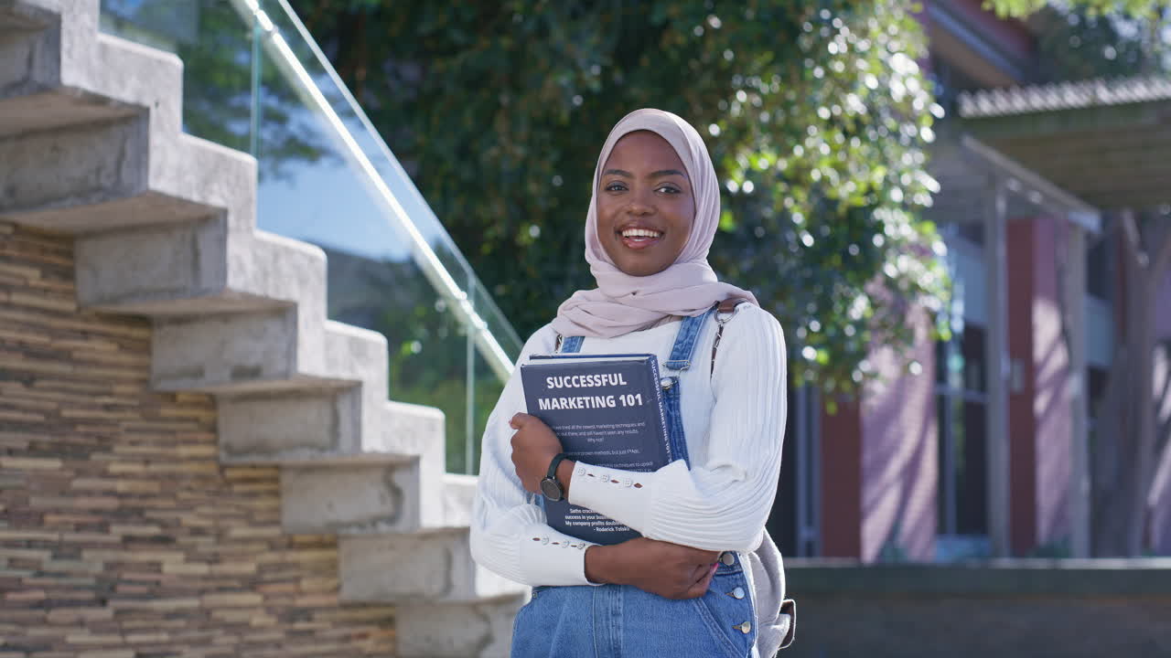 Young woman with textbook outside building