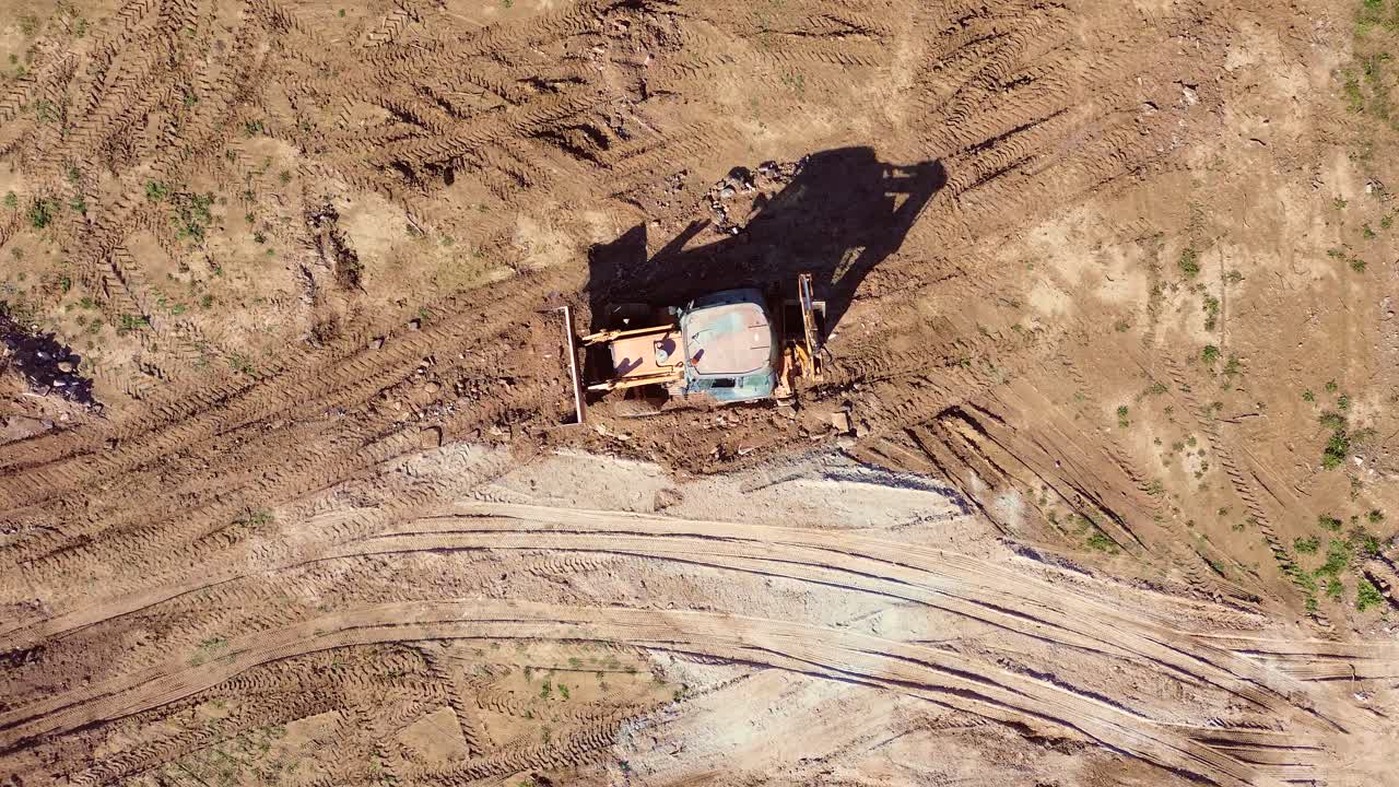 建設現場で掘削機が土を均し、移動させている空撮映像