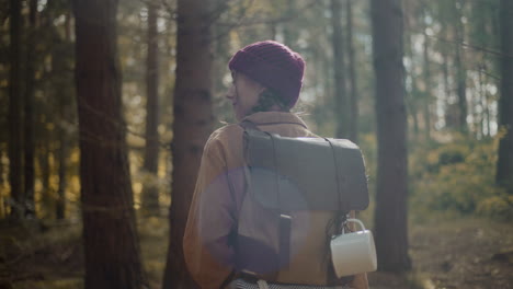 Female-explorer-with-backpack-and-travel-mug-in-forest