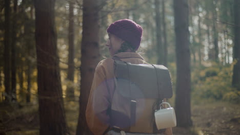 female explorer with backpack and travel mug in forest