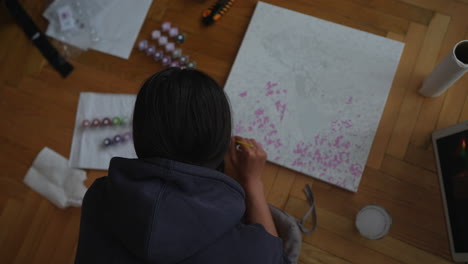 woman painting with dot markers on canvas