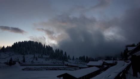 un pueblo de montaña cubierto de nieve invernal con cielo nublado al atardecer - lapso de tiempo