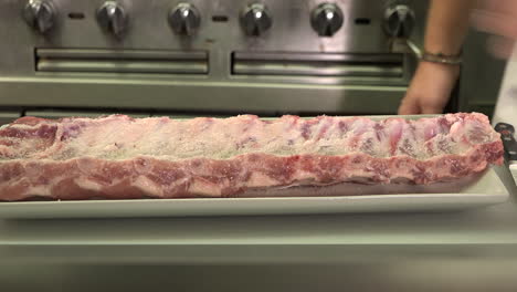 A-beautiful-rack-of-ribs,-raw-being-seasoned-with-sea-salt,-pepper-and-garlic-powder