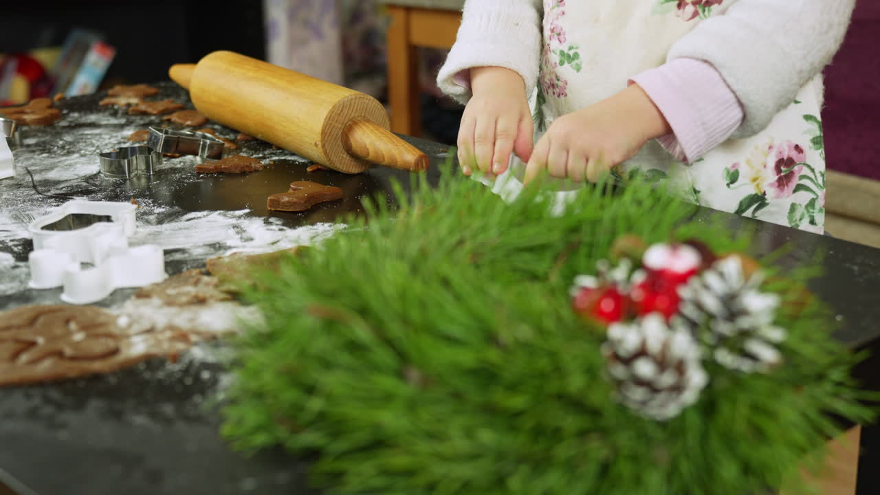 niña preparando galletas de pan de jengibre en la víspera de navidad, usando rodillos y cortadores de galletas
