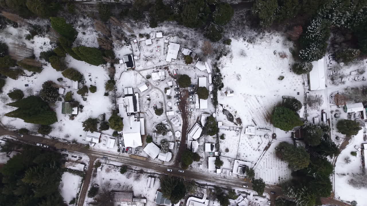 Top-down downward aerial movement of the snow-covered landscape with local streets, Colonia Suiza, Bariloche, Argentina