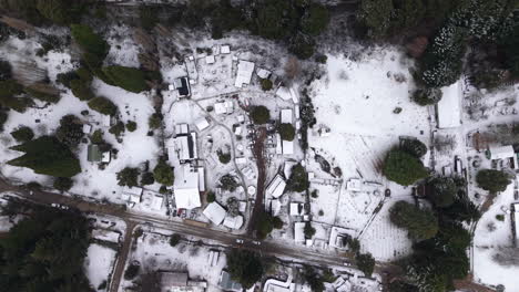 top-down downward aerial movement of the snow-covered landscape with local streets, colonia suiza, bariloche, argentina