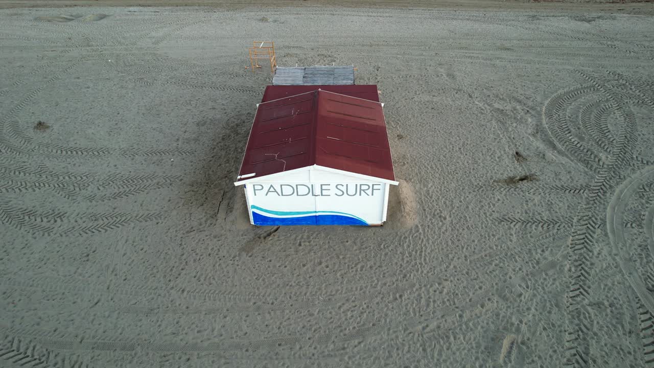 Paddle surf building shack on sandy beach at sunrise by ocean