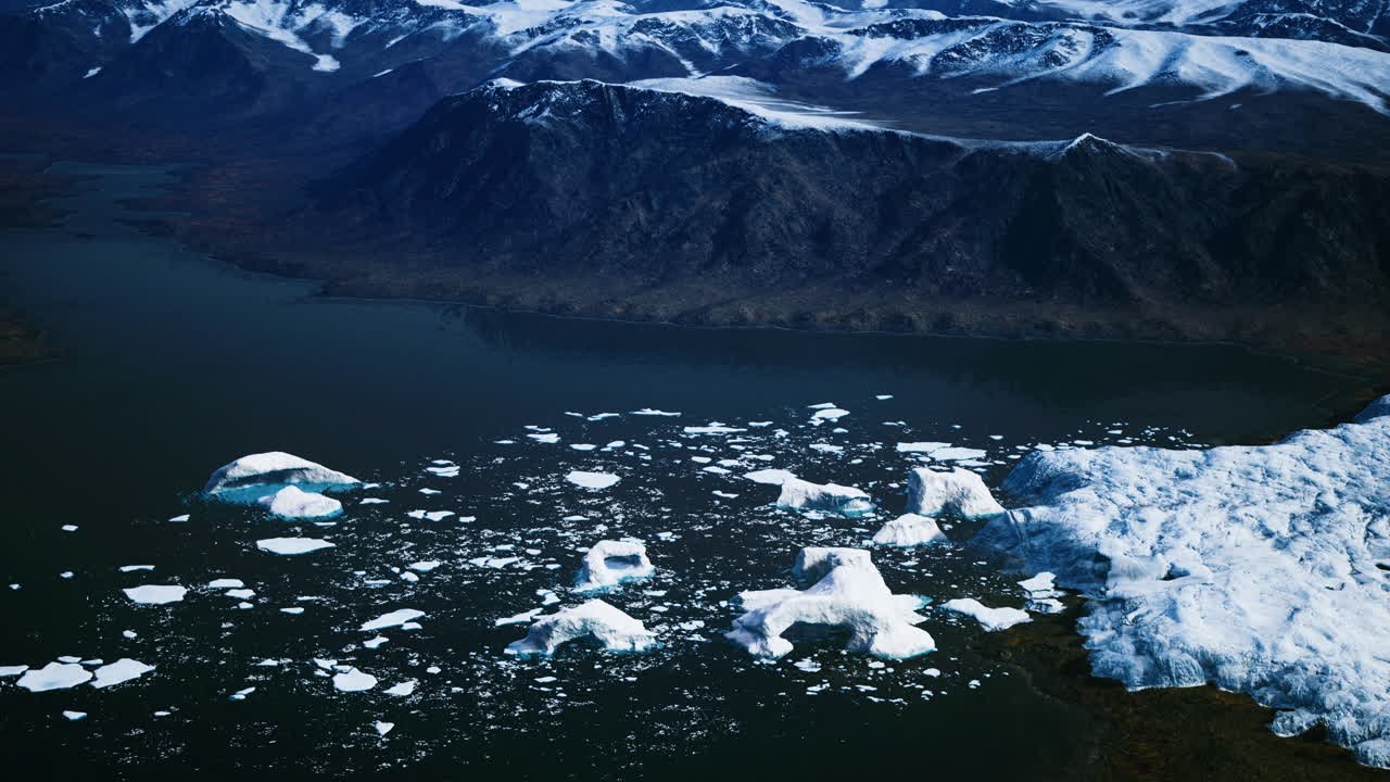 Icebergs floating in a tranquil fjord surrounded by rugged mountains