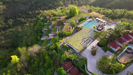 aerial flying over hilltop estate of maua resort and hotel in nusa penida with tropical balinese nature at sunrise, establishing shot