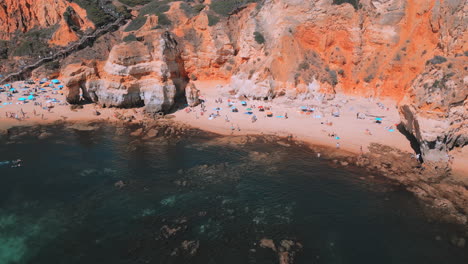 people walking on the beach during the summer in praia dona ana in the algarve in portugal, aerial drone view