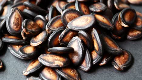 Closeup-of-melon-seeds-in-a-bowl-on-black-background-,