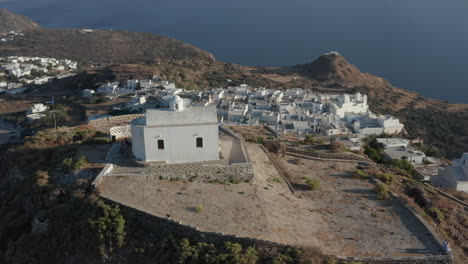 Iglesia-En-La-Cima-De-La-Colina-Con-Bandera-Griega-Ondeando-En-Perspectiva-Aérea-De-Viento