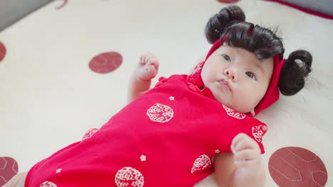 portrait cute asian newborn baby infant girl in chinese traditional red costume, concept of holidays chinese new year