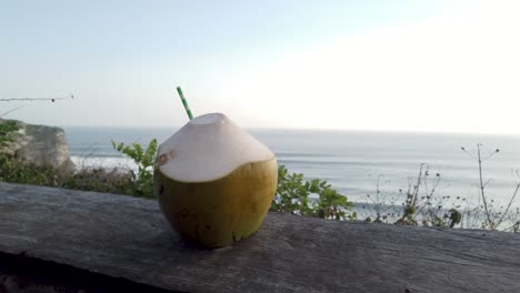 bebidas orgánicas frescas y saludables coco con paja y fondo azul claro del mar y el cielo sobre una mesa de madera