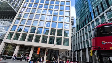 red bus passing by tall modern buildings