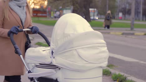 Woman-pushing-elegant-white-stroller-in-suburbs-of-Riga,-close-up-view