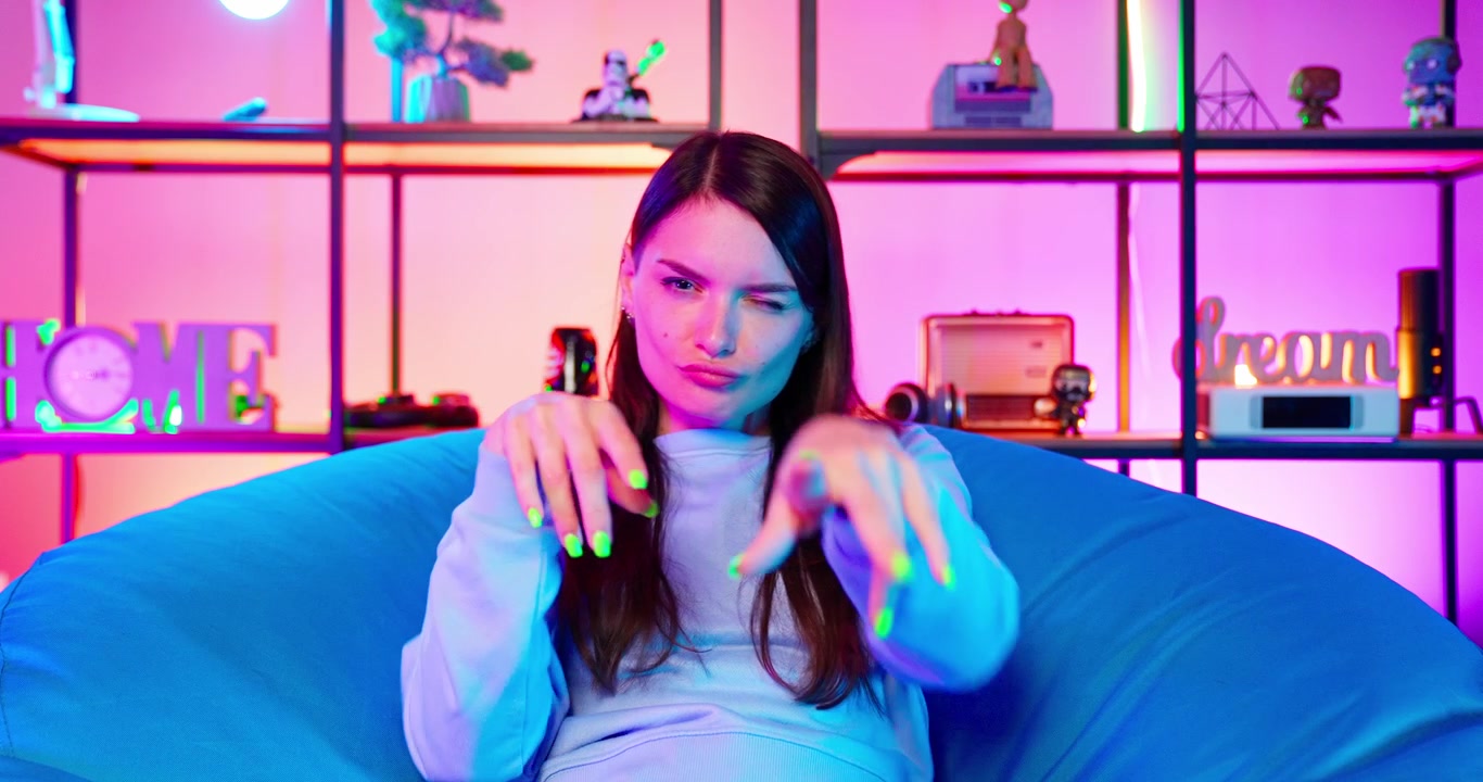 Giovane donna che fa l'occhiolino e gesti giocosi con le mani in una stanza illuminata al neon