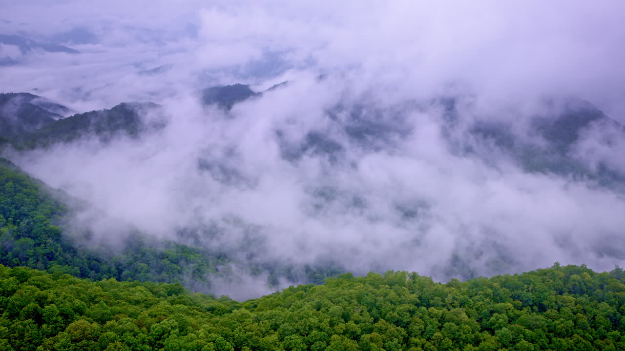 Aerial footage of soft fog rolling over the ancient mountain ridges
