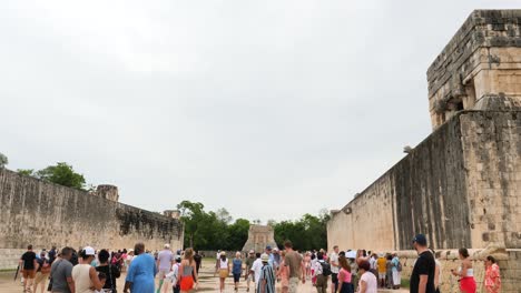 tourists visiting the great ball court in chichen itza.temple of the bearded man or the north temple, in the background.