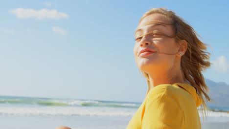 vista lateral de una joven mujer caucásica sacudiendo la cabeza en la playa 4k